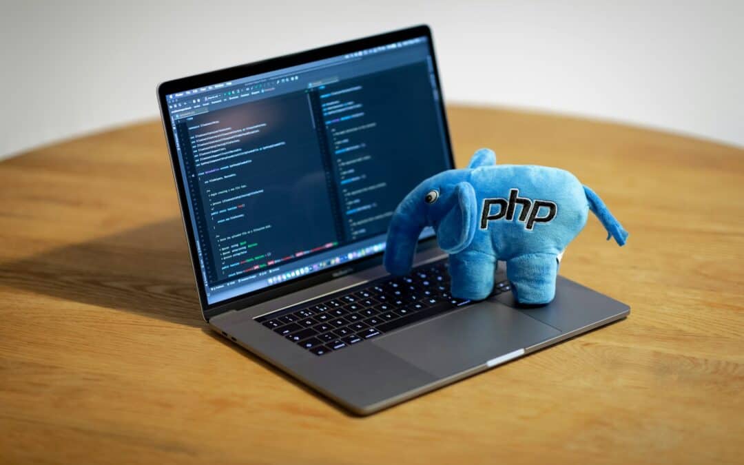 PHP-Elefant als Plüschfigur auf einem Laptop mit Programmcode